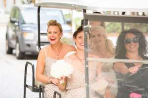 A bride and her bridal party smile as they are driven around in a go cart. Photo: Rae Leytham Photography.