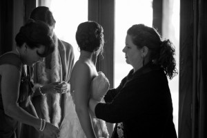 Rae Leytham holds a bride's dress as the mother of the bride ties the corset. Photo: Rae Leytham Photography.